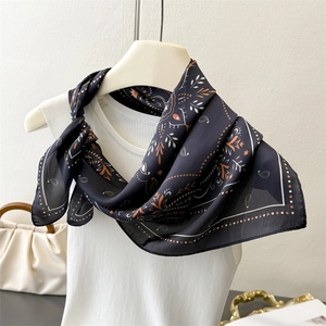 Detail of silk-like scarf featuring navy paisley patterns and ornate floral borders