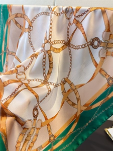 Detail of emerald green silk square scarf with vintage gold chain and buckle patterns
