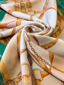 Detailed macro view of equestrian print silk scarf with chain patterns and satin texture