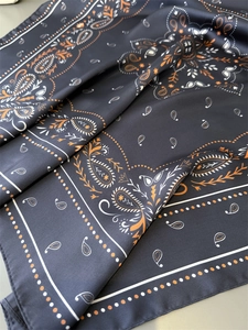 Macro shot of paisley print silk scarf in navy blue and orange with luxurious texture
