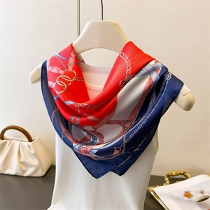 Close-up of equestrian silk scarf with red and navy chain patterns draped on a white mannequin