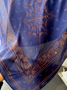 Detailed macro view of navy and orange paisley silk scarf texture with floral patterns