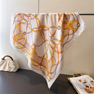 Detail of silk scarf featuring equestrian chain prints draped over a metal bar