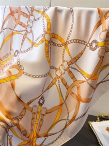 Close-up of silk scarf with equestrian horse bit print and elegant chain patterns