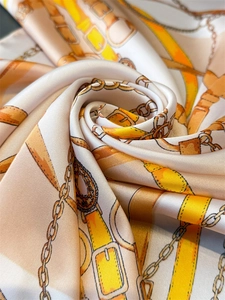 Detailed view of silk scarf with equestrian horse chain prints and satin texture