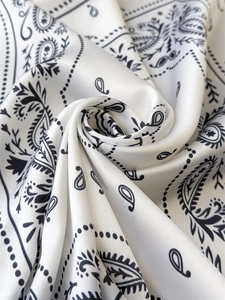 Macro shot of white silk scarf with black paisley pattern and elegant satin texture