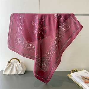 Detailed view of dark red paisley silk scarf draped elegantly with luxury accessories