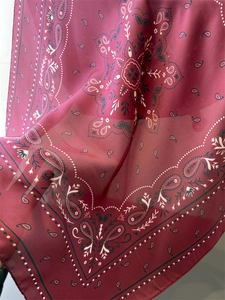 Detail of burgundy paisley silk scarf showing soft chiffon texture and rolled edges