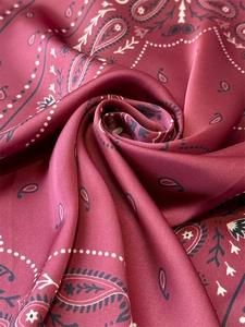Detailed macro view of deep red paisley satin silk scarf with premium glossy texture