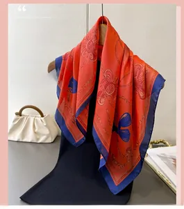 Close-up of chain print silk square scarf with orange and navy blue contrast borders