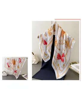 Macro shot of silk-like square scarf featuring classic golden chain and red bow patterns