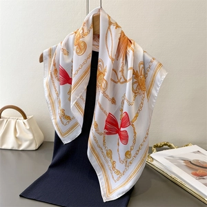 Silk-like satin scarf with golden chain and red bow print draped on a model