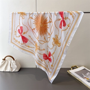 Close-up of square silk scarf with chain prints and elegant red bow pattern detail