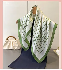 Detailed view of white silk-like square scarf with green geometric line print on hanger