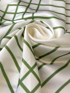 Detail of silk satin scarf featuring dark green grid pattern on creamy white fabric
