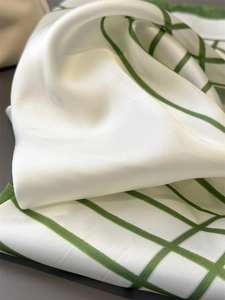 Close-up of cream and green plaid silk scarf showing smooth texture and lustrous sheen