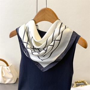 Elegant white square silk scarf with black geometric line patterns on a stylish outfit