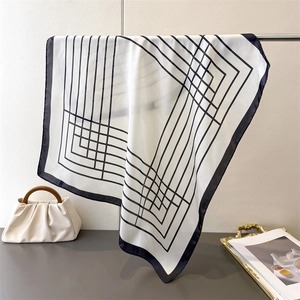 Close-up of silk scarf with geometric black lines draped on a metal stand for soft texture