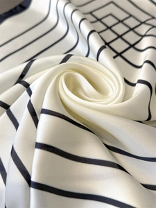Macro shot of faux silk scarf showing smooth texture with black geometric line prints
