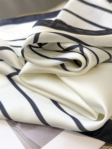 Close-up of elegant white silk scarf with minimalist black stripe pattern and smooth texture