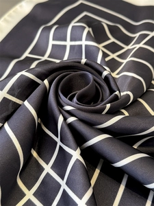 Macro view of black and white checkered silk scarf folded into a rose shape detail