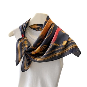 Elegant navy silk-like square scarf with gold chain and red feather print on model