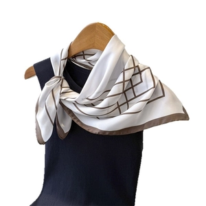 Elegant silk scarf with brown geometric grid lines tied on a black top on wooden hanger