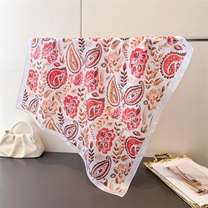 Detailed close-up of paisley silk scarf draped over a metal bar with elegant handbag