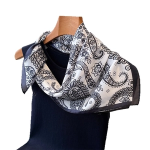 Elegant black and white paisley print silk scarf displayed on a ribbed vest mannequin