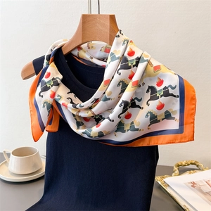 Détail d'un foulard en soie à imprimé équestre drapé sur un pull en maille bleu marine