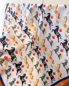 Gros plan sur un foulard en soie montrant un tissu satiné et un motif de cheval coloré