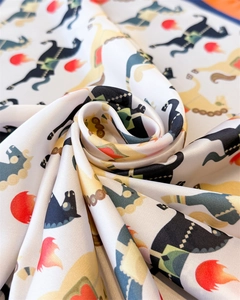 Détail d'un foulard en soie avec motifs de chevaux abstraits et flammes sur fond blanc