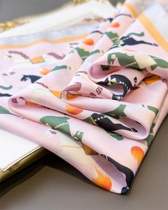 Détail de la texture d'un foulard en soie avec motifs de chevaux et bords orange