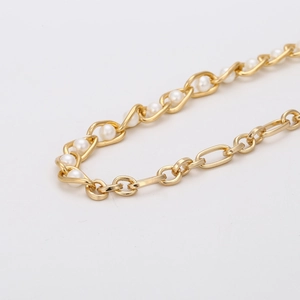 Collier chic en chaîne dorée et perles blanches sur un fond blanc au style minimaliste
