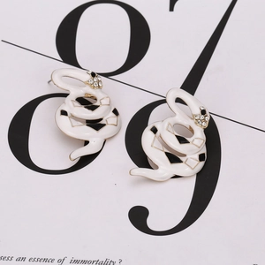 Minimalist snake-shaped earrings in white enamel with crystal accents on a white background