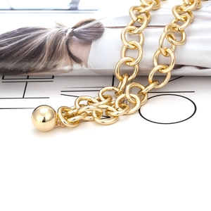 Collana a catena dorata spessa con ciondolo a sfera in metallo liscio su rivista di moda