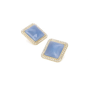 Macro view of square blue marble resin stud earrings with white diamond border