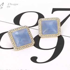 Macro shot of geometric square stud earrings featuring light blue resin and crystals