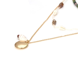 Close-up of bohemian layered necklace featuring gold metal charms and natural shells