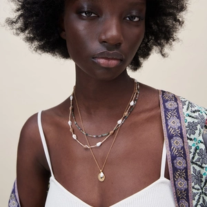 Three-layer bohemian necklace set with seashells, beads and a gold pendant on a model