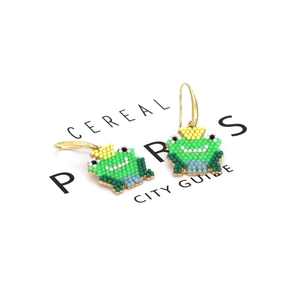 Handmade green beaded frog earrings with colorful accents and gold hooks on white card