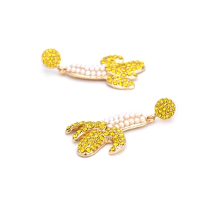 Exaggerated yellow rhinestone banana earrings with white pearls on a gold base