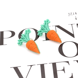 Close-up of cute carrot resin stud earrings with vibrant orange and green colors