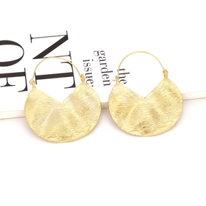 Vintage gold geometric textured fan-shaped drop earrings displayed on a magazine background