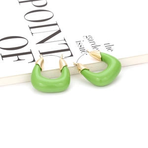 Gros plan sur des boucles d'oreilles créoles en résine verte en forme de U avec accents dorés