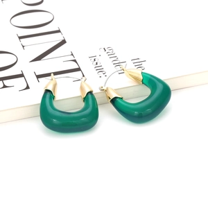 Détail de boucles d'oreilles en résine vert foncé en forme de U avec bord doré