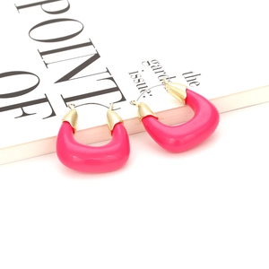 Détail de boucles d'oreilles en résine rose en forme de U avec fermoirs dorés