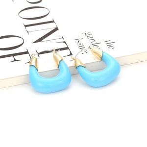 Gros plan de boucles d'oreilles en résine bleue en forme de U avec clous dorés