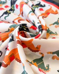 Détail d'un foulard en soie avec texture lisse et imprimé de chevaux colorés