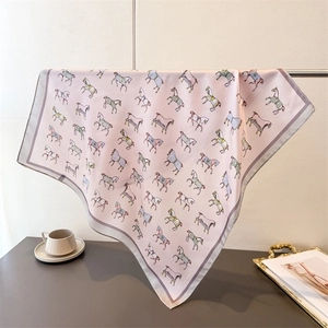 Close-up of pink silk scarf with pony print hanging on a metal rack for texture
